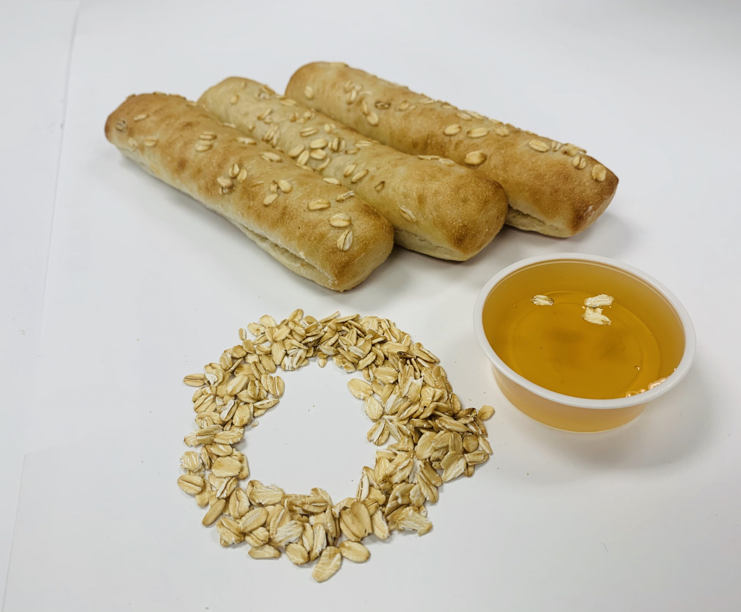 Oat-topped artisan bread sticks with honey
